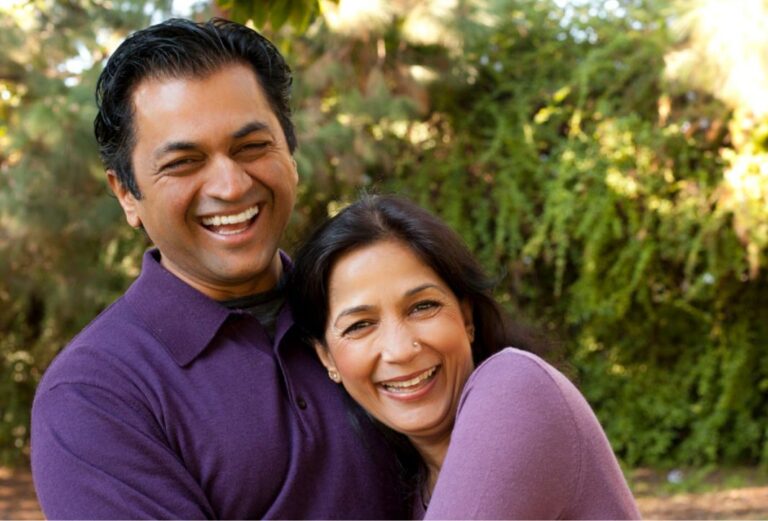 Couple hugging and smiling. Both are wearing purple shirts.