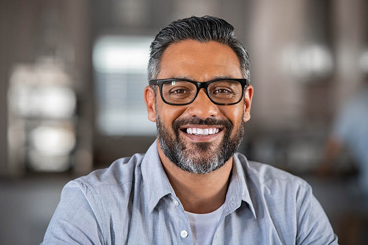 Smiling adult man wearing spectacles and looking at camera.